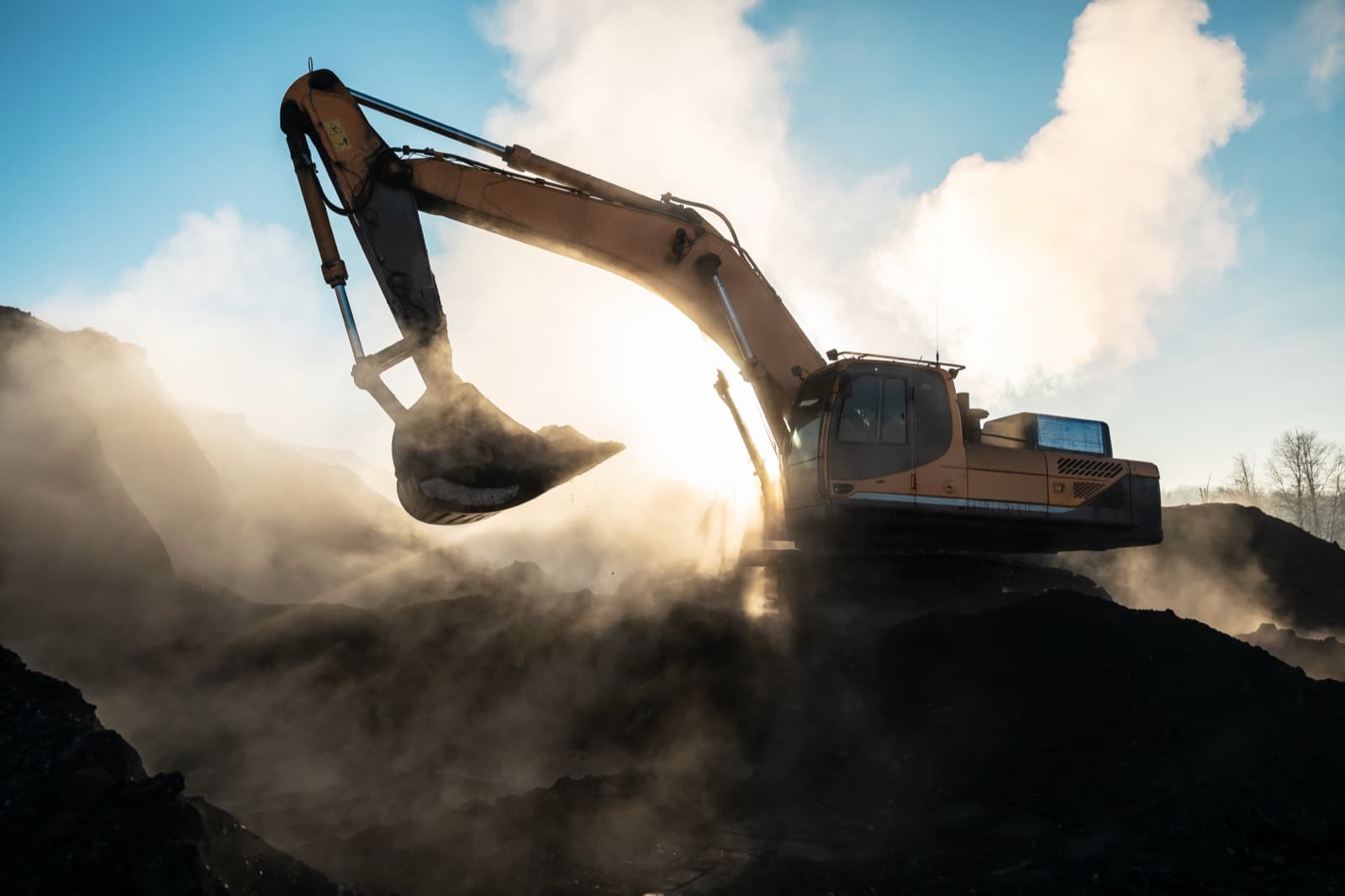 An excavator working on a dusty site at first light