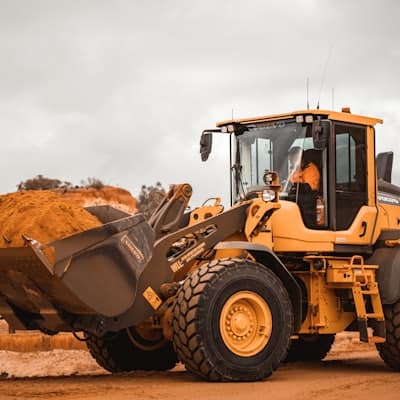 A wheel loader carrying a full bucket on a work site